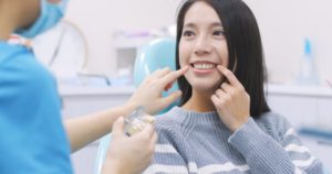 Woman smiling pointing to teeth.